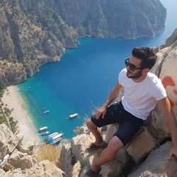 Man sitting on rock by sea