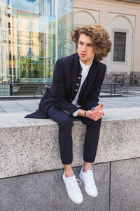 Full length of man looking away sitting in city