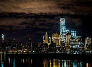 Illuminated one world trade center by east river in manhattan at night