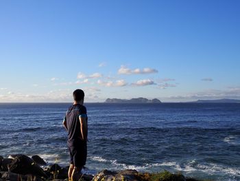 Rear view of man looking at sea against sky