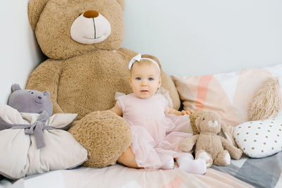 Funny cute little girl of 1 year, sitting on the bed in the morning with a bow