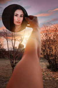 Portrait of beautiful young woman against sky during sunset