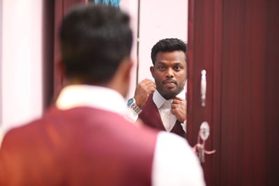 Man getting dressed reflecting in mirror