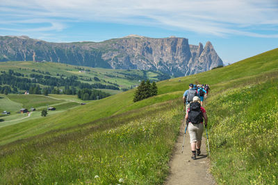 Hikers in an idyllic alp valley with flowering meadows and mountains