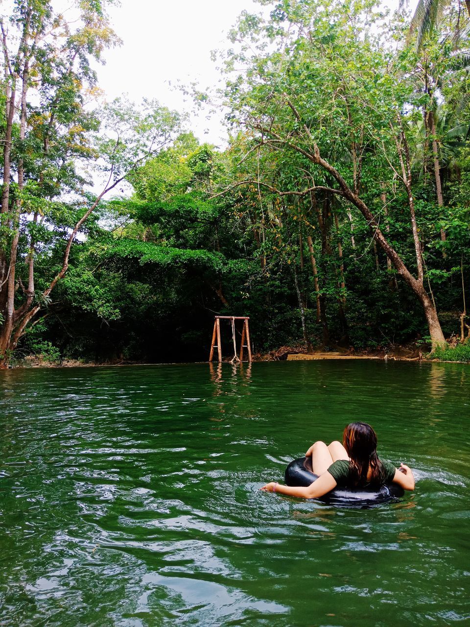 tree, water, plant, leisure activity, waterfront, real people, lake, lifestyles, one person, day, nature, relaxation, green color, adult, young adult, vacations, holiday, women, outdoors, floating on water, inflatable