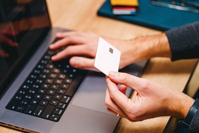 Cropped hands of man using laptop