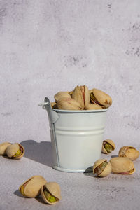 Pistachios in white bucket on concrete background. healthy and dietary nutrition. concept of nuts. 