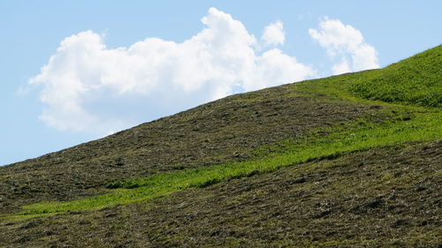 Low angle view of green hill against blue sky