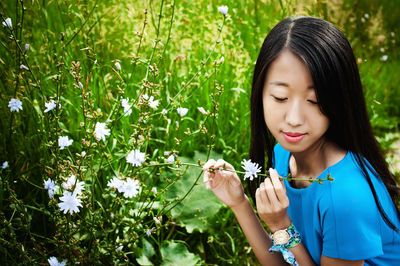 Close-up of young woman by flowering plants in forest