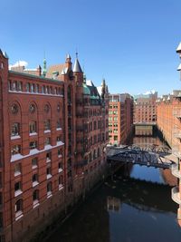 Arch bridge over river by buildings against sky in city