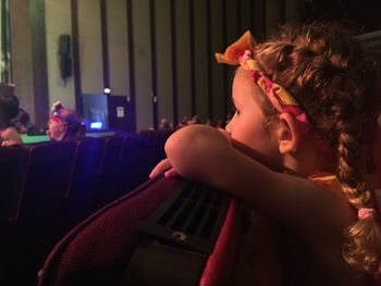 Side view of girl watching performance in stage theater