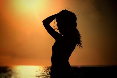 Silhouette woman standing by sea against sky during sunset