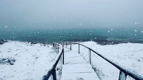 Snow covered staircase by sea during winter