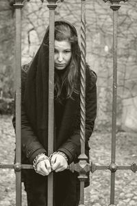 Sad woman tied with chain on gate against wall