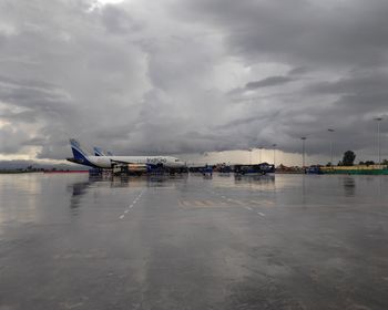 Airplane on wet airport runway against sky