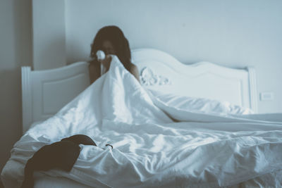 Terrified woman sitting on bed with bra in foreground