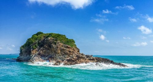 Scenic view of rock formations amidst sea against blue sky