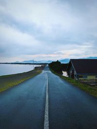Empty road amidst buildings in city against sky
