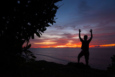 Silhouette man standing at beach against sky during sunset