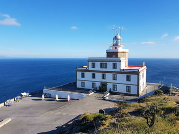 Lighthouse amidst sea and buildings against sky