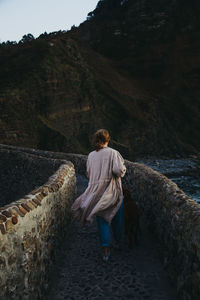 Rear view of woman walking on rock