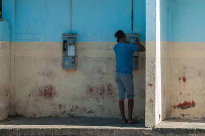 Rear view of man standing against door of building