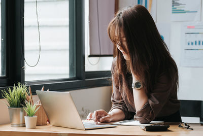 Woman using phone while sitting on table