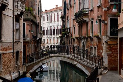 Arch bridge over canal amidst buildings in city
