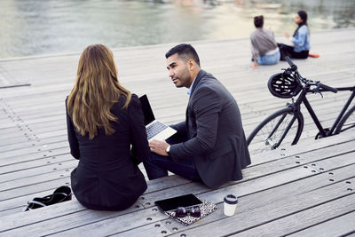 Business coworkers discussing while sitting on floorboard