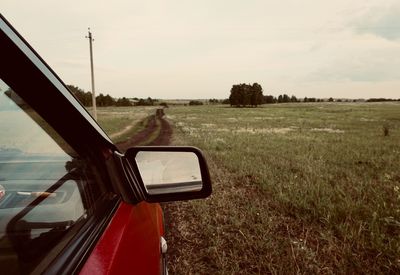 Car on road amidst field against sky