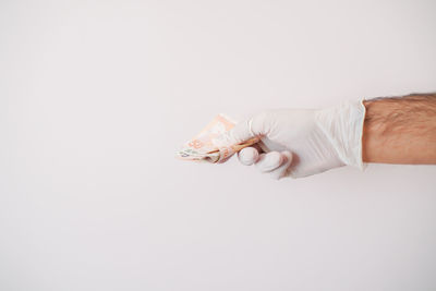 Close-up of hand holding paper over white background