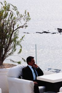 Businessman looking at sea while sitting on chair