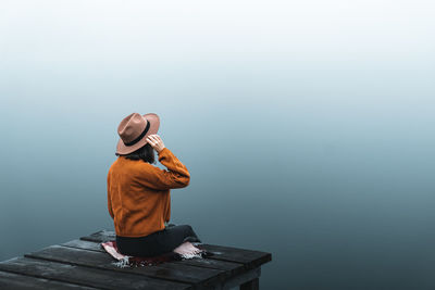 Rear view of woman sitting on retaining wall