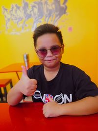 Portrait of boy wearing sunglasses sitting on table