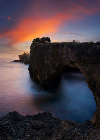 Rock formations in sea against sky during sunset