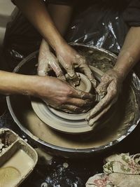 Midsection of man making pot with coworker