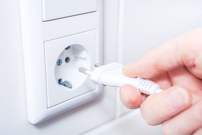 Close-up of hand plugging electric cord