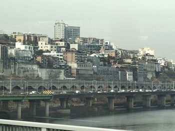 Buildings by river against sky in city