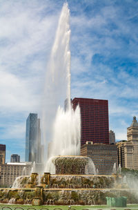 Water splashing against fountain in city against sky