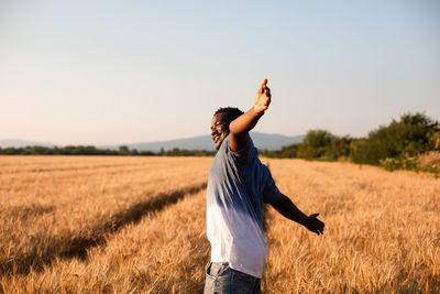 Smiling man with arms raised standing on field