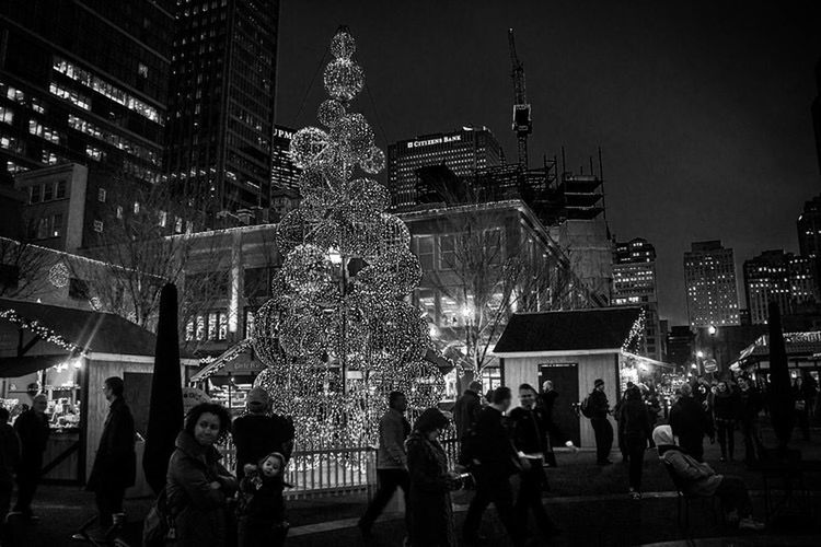 CROWD AT ILLUMINATED CHRISTMAS TREE AT NIGHT