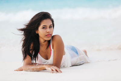 Portrait of young woman lying on beach