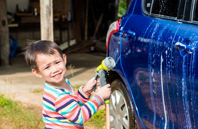 Portrait of cute boy washing car outdoors