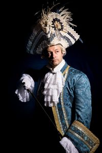 Confident man in venice carnival costume against black background