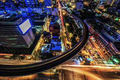 High angle view of light trails on street amidst buildings in city at night