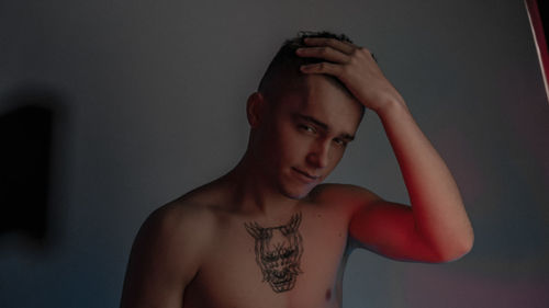 Portrait of young man standing against wall