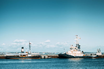 Boats sailing in sea against blue sky