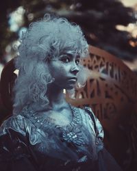 Teenage girl with silver body paint looking away