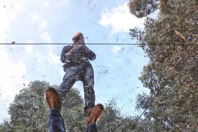 Low angle view of men standing by tree against sky