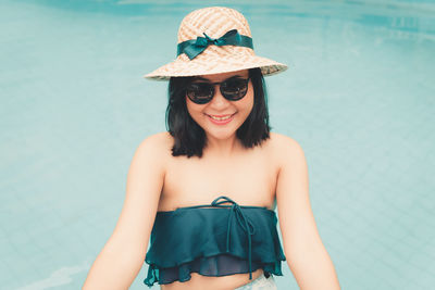 Portrait of smiling woman wearing sunglasses standing in swimming pool